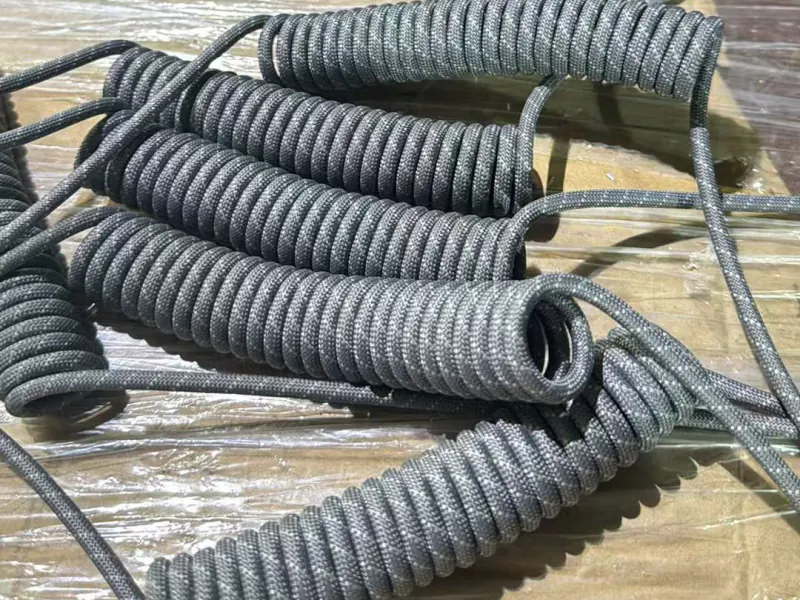 Grey braided coiled cables stacked on packing cardboard at the supplier